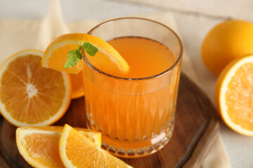 Glass of fresh orange juice with mint and cut fruits on white background