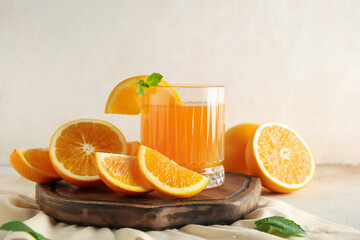 Glass of fresh orange juice with mint and cut fruits on white background