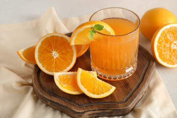 Glass of fresh orange juice with mint and cut fruits on white background