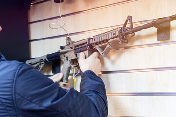 A man with an automatic rifle in a gun store.
