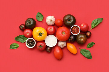 Fresh ripe tomatoes and different spices on red background