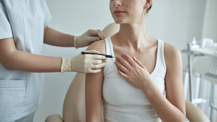 A woman is sitting in a chair while a doctor performs a procedure on her. The woman is relaxed and comfortable, and the doctor is wearing gloves and a mask