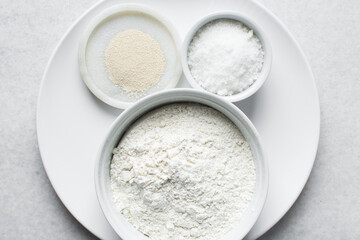 Overhead view of mise en place of ingredients for making nigerian puff-puff, flatlay of flour yeast sugar for puff-puff on a marble countertop, process of making puff-puff or bofrot