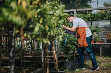 A young gardener with down syndrome carefully tends to plants in a greenhouse, highlighting...
