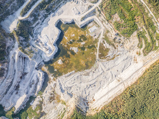 Stone quarry in the forest. Flying over the summer mixed forest during sunset. The surroundings of Yekaterinburg. Ural, Russia, Aerial View