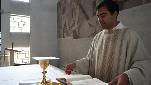 Priest leafing through missal book at mass in catholic church.