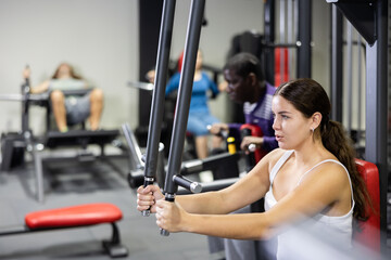 Fototapeta premium Caucasian woman training on chest fly machine in gym