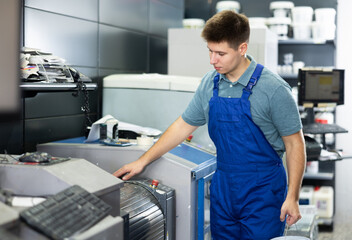 Male worker and paint mixing machine in local hardware store