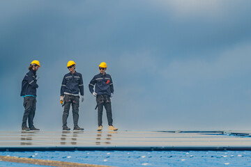 Worker Technicians are working to construct solar panels system on roof. Installing solar photovoltaic panel system. Men technicians walking on roof structure to check photovoltaic solar modules.