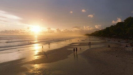 This aerial view showcases Playa Santa Teresa in Puntarenas, Costa Rica, with a vibrant sunset over the beach as people enjoy the peaceful atmosphere and tranquility of the evening