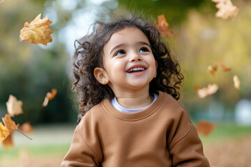 Arabian little girl smiling wearing sweatshirt playing at sunny autumn park
