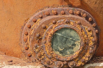 Porthole of an old rusted diving bell