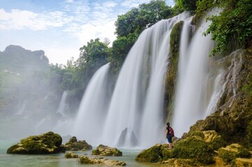 Fototapeta premium Woman in Front of Majestic Waterfall Surrounded by Stunning Nature