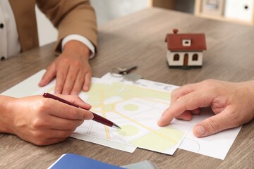 Real estate agent working with client at wooden table, closeup