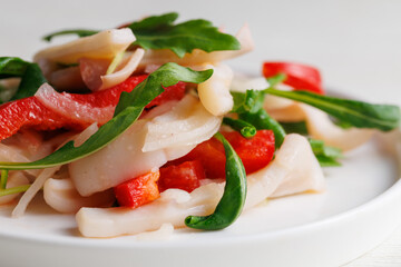 salad with boiled squid, sweet red paprika pepper, onion and arugula, with dressing, restaurant, no people, Healthy seafood eating concept, macro close up