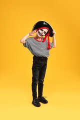 Funny boy dressed like pirate on yellow background. Halloween costume