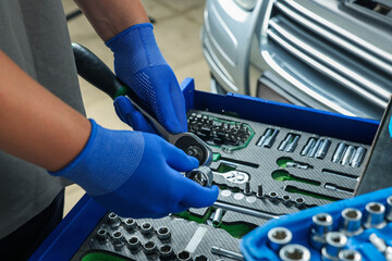 Auto mechanic with different tools at automobile repair shop, closeup