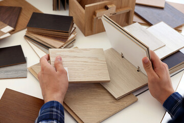 Man choosing wooden flooring among different samples at table, closeup