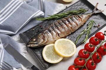 Delicious grilled mackerel, rosemary, lemon and tomatoes on grey table, closeup