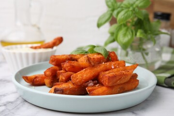 Sweet potato fries and basil on white marble table, closeup