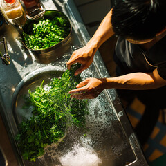 Chef washes herbs in kitchen