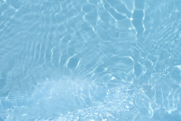 Obraz premium Blue water with ripples on the surface. Defocus blurred transparent blue colored clear calm water surface texture with splashes and bubbles. Water waves with shining pattern texture background.