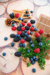 Mix of blackberry blueberry raspberry black currant in wicker baskets isolated on wooden background, horizontal image