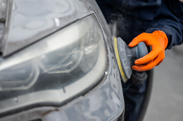 A mechanic sands the putty on a car body with a machine. Repair after an accident. 