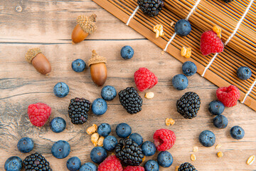 Close-up on blackberries, blueberries, raspberries and granola, top view flat lay on a wooden table background