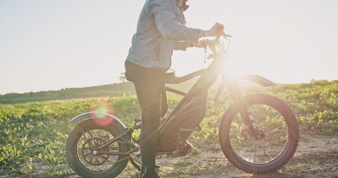 E bike, cycling and sunset with person in nature for sustainability, travel and relax. Peace, environment and speed with ride on dirt path trail for challenge, carbon footprint and transportation
