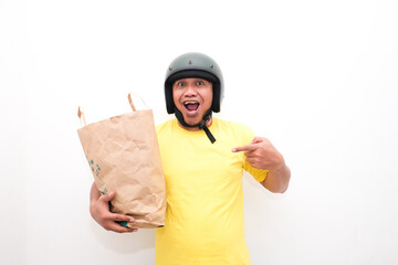 Portrait of Asian online courier driver wearing tshirt and helmet giving craft paper shopping bag with gift inside. Isolated image on white background