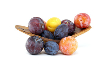 Variety of fresh plums in a wooden bowl showcasing vibrant colors