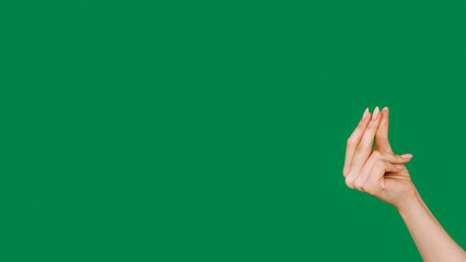 Finger snapping. Rhythm gesture. Raised female hand pinching something invisible isolated on green empty space advertising background.