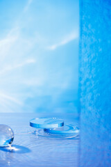 The skincare advertisement template features a product display area with two circular glass platforms, a lake, frosted panels, and a glass sphere against a light blue backdrop.