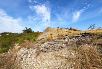Hill landscape with storm clouds, forming tornado, dramatic weather scene, dark skies over rolling hills.