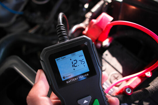 Battery tester in a auto mechanic hand for battery voltage or battery health analysis , good voltage , Car maintenance concept