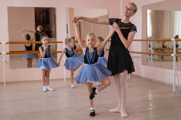 Obraz premium Children's ballet school. Caucasian woman teaching ballet to little girls. 