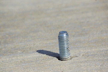 Shiny silver screw in sidewalk