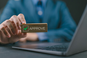 Businessman holding wooden block with text approve for document approval, assessment, approve the loan, finance agreement, loan, stamp, business.