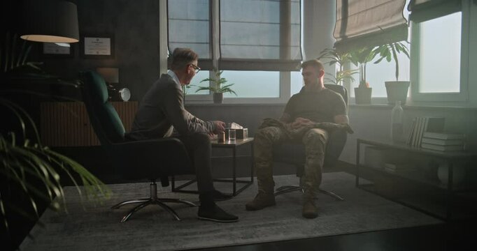 Professional therapist conducts psychotherapy session or psychological post war rehabilitation for military man. Senior psychiatrist gives sedative drugs or antidepressants to soldier with PTSD.