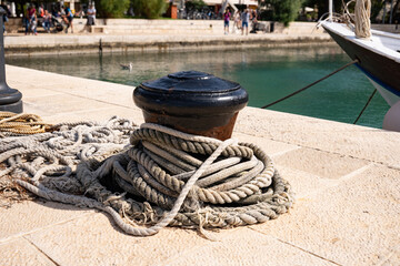 Fototapeta premium Close-up of a bollard with many ship ropes wrapped around it in the port of the fishing village of Fažana, Croatia