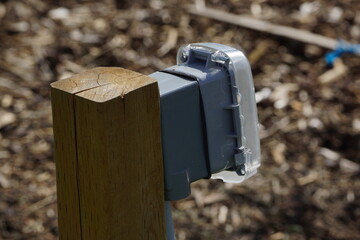 Outdoor outlet with protective cover on grass and wood bark chips