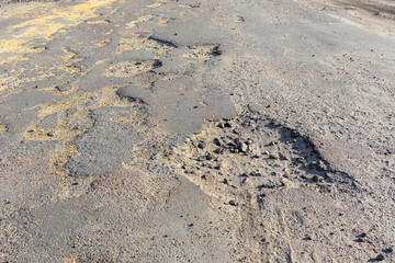 Bad road, cracked asphalt with potholes and big holes. Potholes on the road with stones on the asphalt. The asphalt surface is destroyed on the road. Bad condition of the road, needs repair.