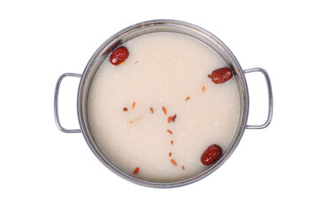 A round metal pot filled with a cloudy white broth, simmering with red dates.