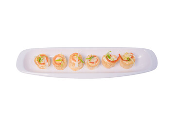 A rectangular plate holds a row of bite-sized rolls filled with a creamy filling and topped with fresh chives.