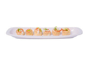 A rectangular plate holds a row of bite-sized rolls filled with a creamy filling and topped with fresh chives.