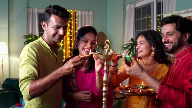 Two happy Indian couples share bright smiles and bonding moments while lighting samai with diyas celebrate Diwali in joyful spirit