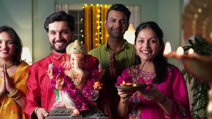 Indian family dressed in traditional attire,joyfully welcomes Ganapati Bappa with a lighted samai and pooja thali,embracing the festive spirit of Ganesh Chaturthi with love and devotion