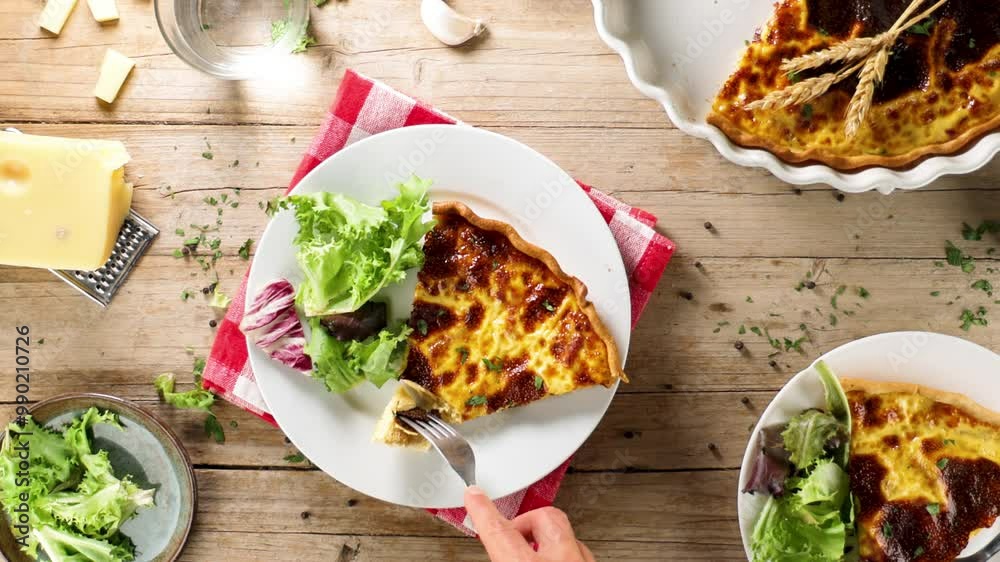 Canvas Prints Top view of a plate with a slice of quiche and salad, with a hand holding a fork – a delicious and balanced meal, perfect for lunch or brunch.
