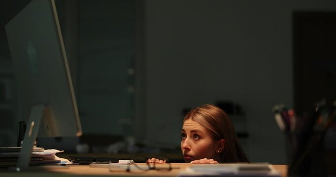 Office female worker reacts to frightening lightnings behind window picking out of desk. Woman expresses fear staying along in corporate office